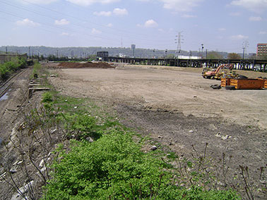 Large gravel lot with vegetation growing along the side of it