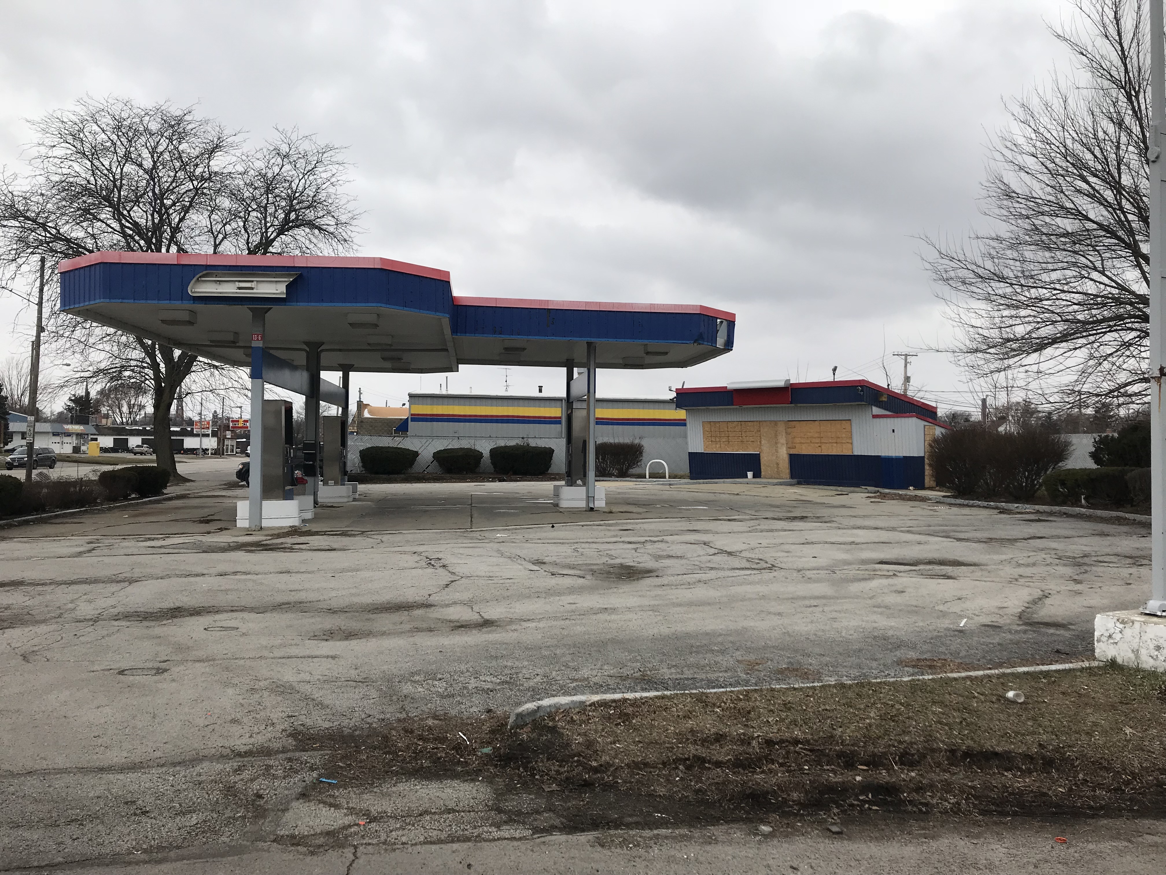 Gas station that is boarded up and empty on an overcast day