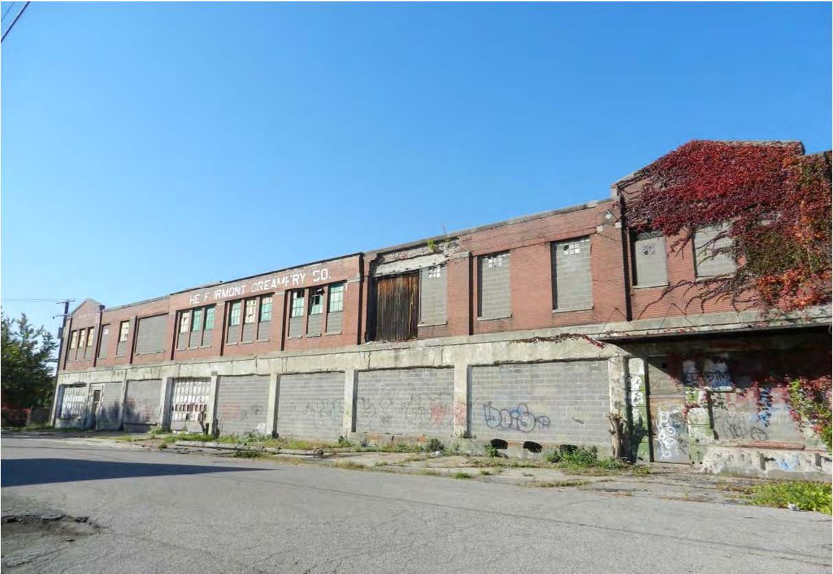 The Fairmont Creamery Company building with broken windows, graffiti on lower parts of the building, and vegetation climbing up the brick